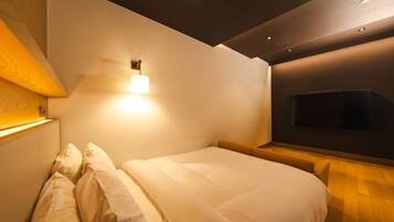 A modern bedroom with a bed, a wall-mounted TV, and recessed lighting.