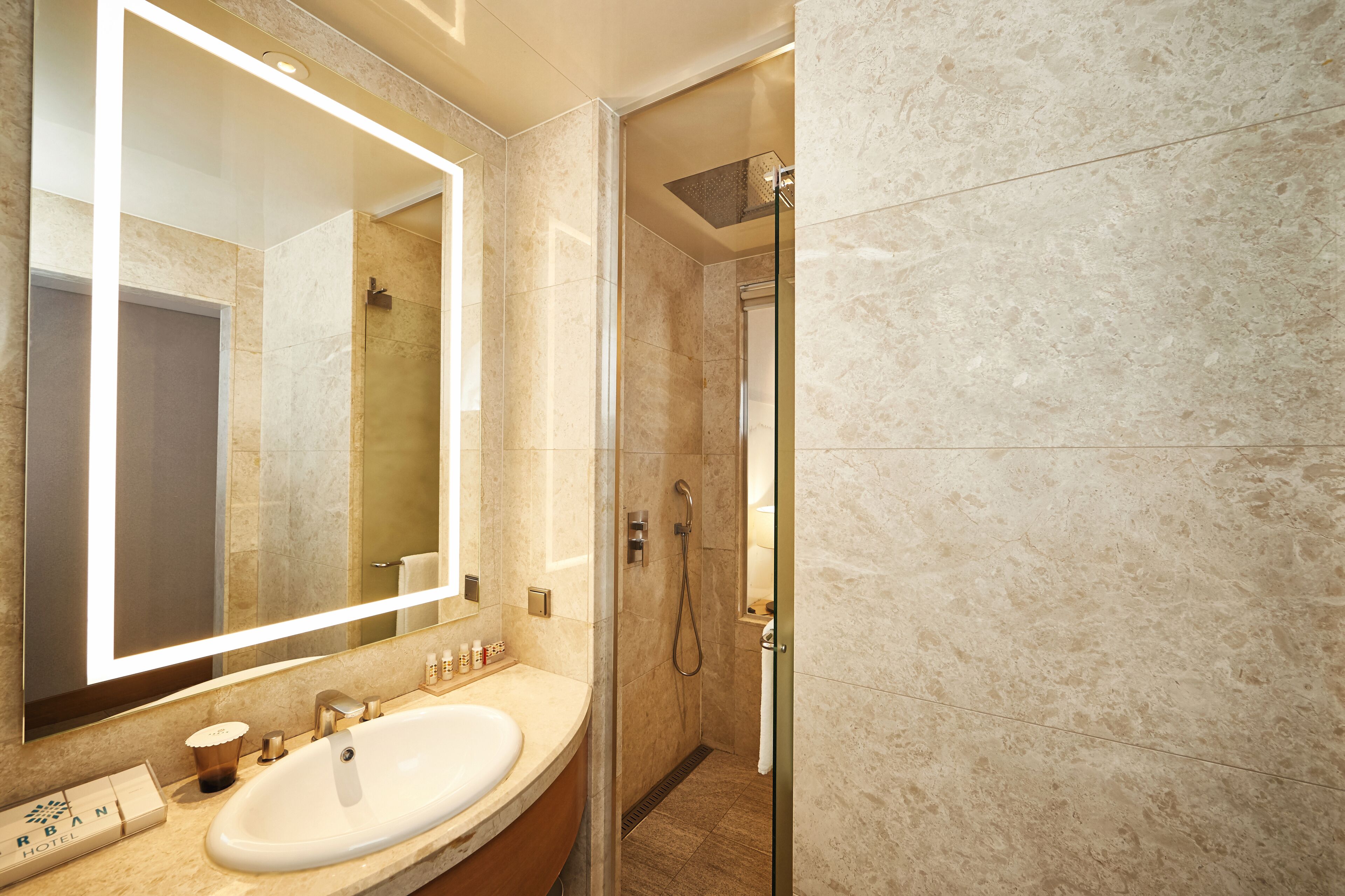 A modern bathroom with a large mirror, a sink, and a shower area.