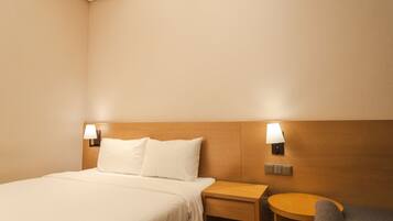 A hotel room with a bed, a nightstand, a lamp, and a small round table.