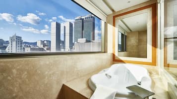 A modern bathroom with a large window, a bathtub, and a mirror.
