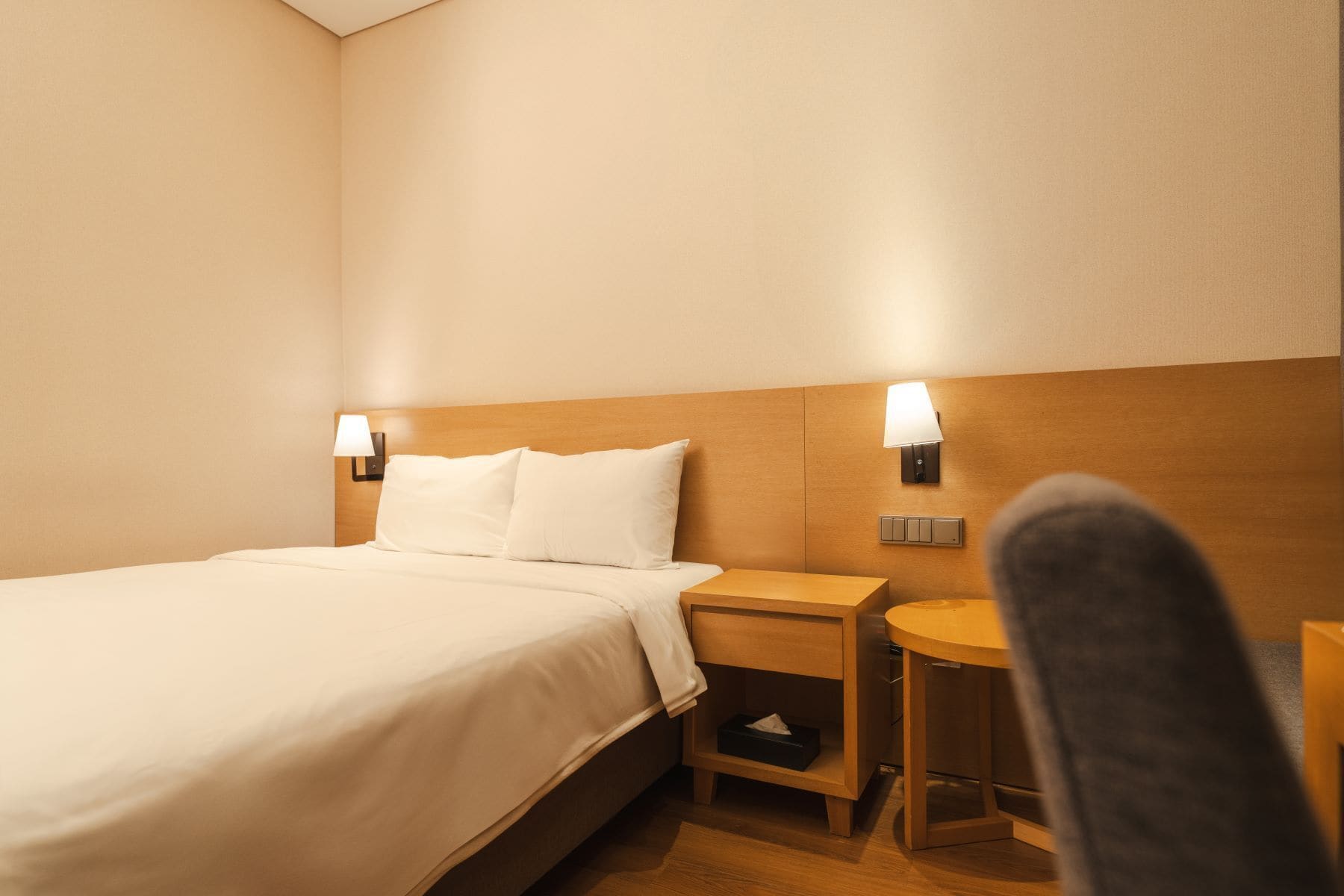 Een hotelkamer met een bed, twee nachtkastjes en een stoel.