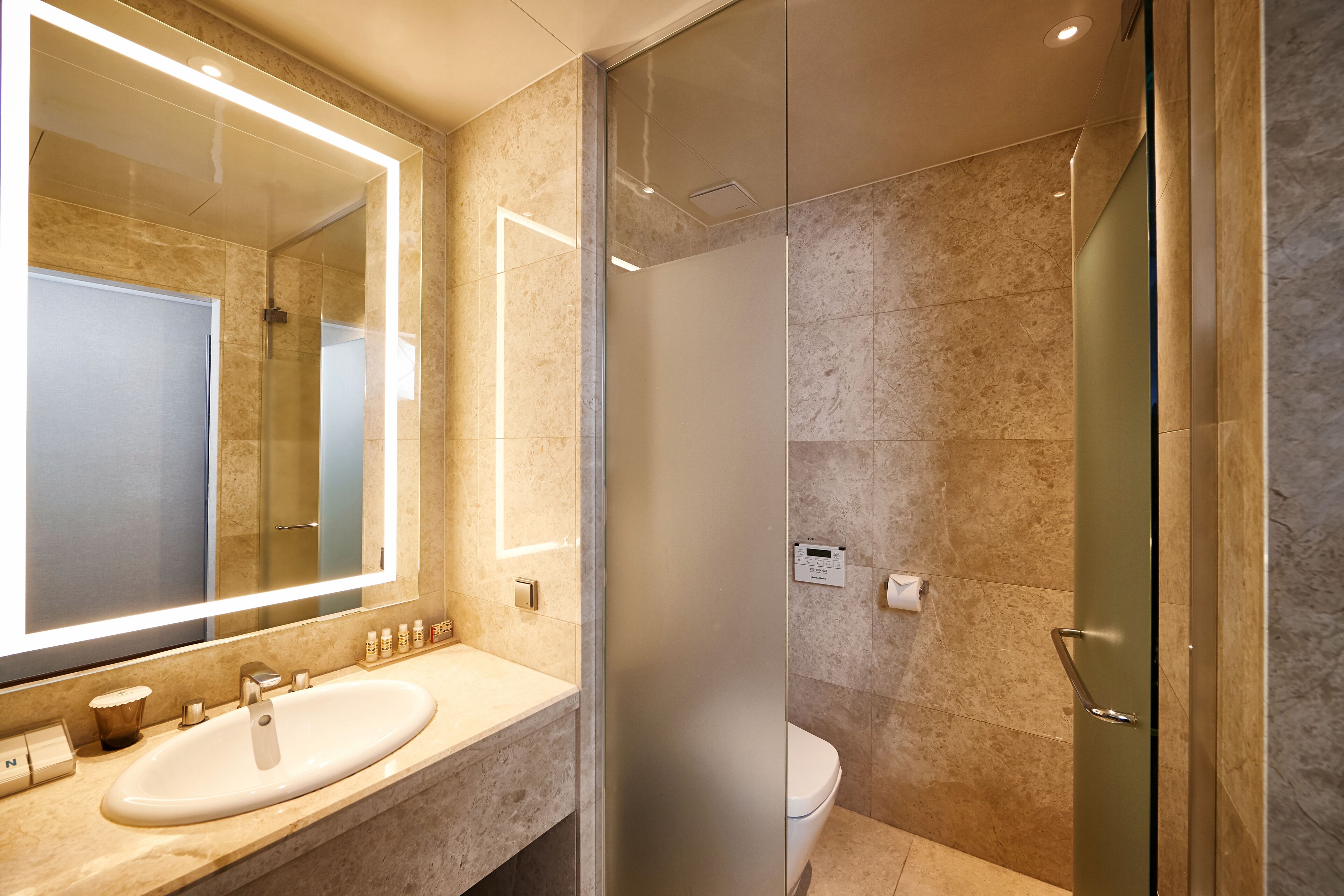 A modern bathroom with a large mirror, a sink, and a toilet.