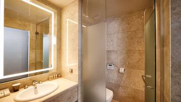 A modern bathroom with a large mirror, a sink, and a toilet.