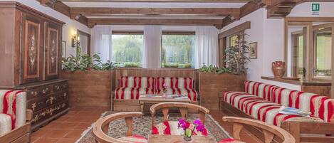 A traditional inn with wooden furniture, a fireplace, and a view of the forest.