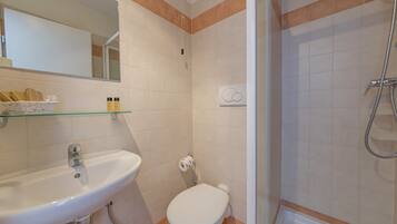 A bathroom with a white sink, toilet, and shower.