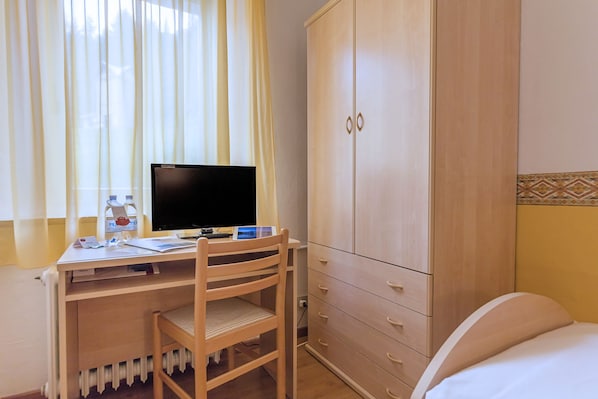 A room with a wooden desk, a computer, a chair, a wardrobe, and a bed. - Hotel Sorapiss (Auronzo di Cadore)