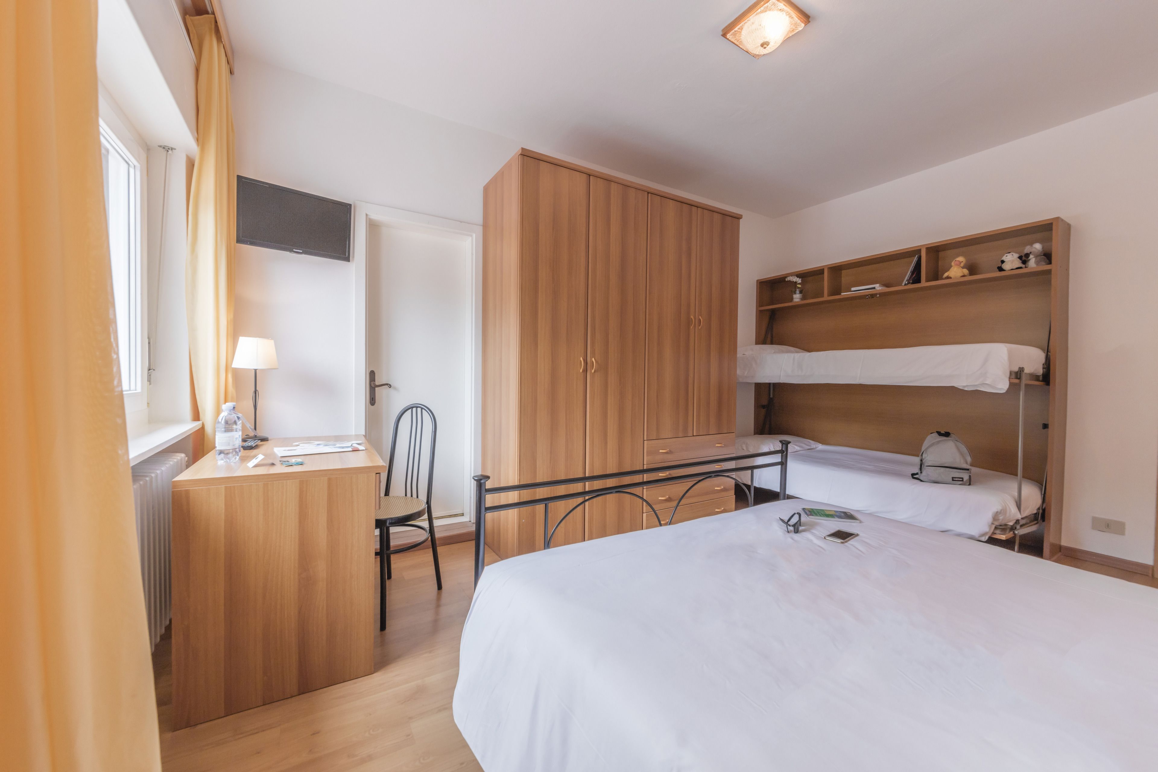 A bedroom with a bed, a desk, a chair, and a wardrobe.
