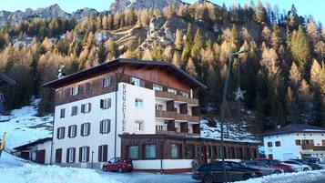 Ein mehrstöckiges Hotel mit einem Schild mit der Aufschrift SORAPISS und Blick auf schneebedeckte Berge.