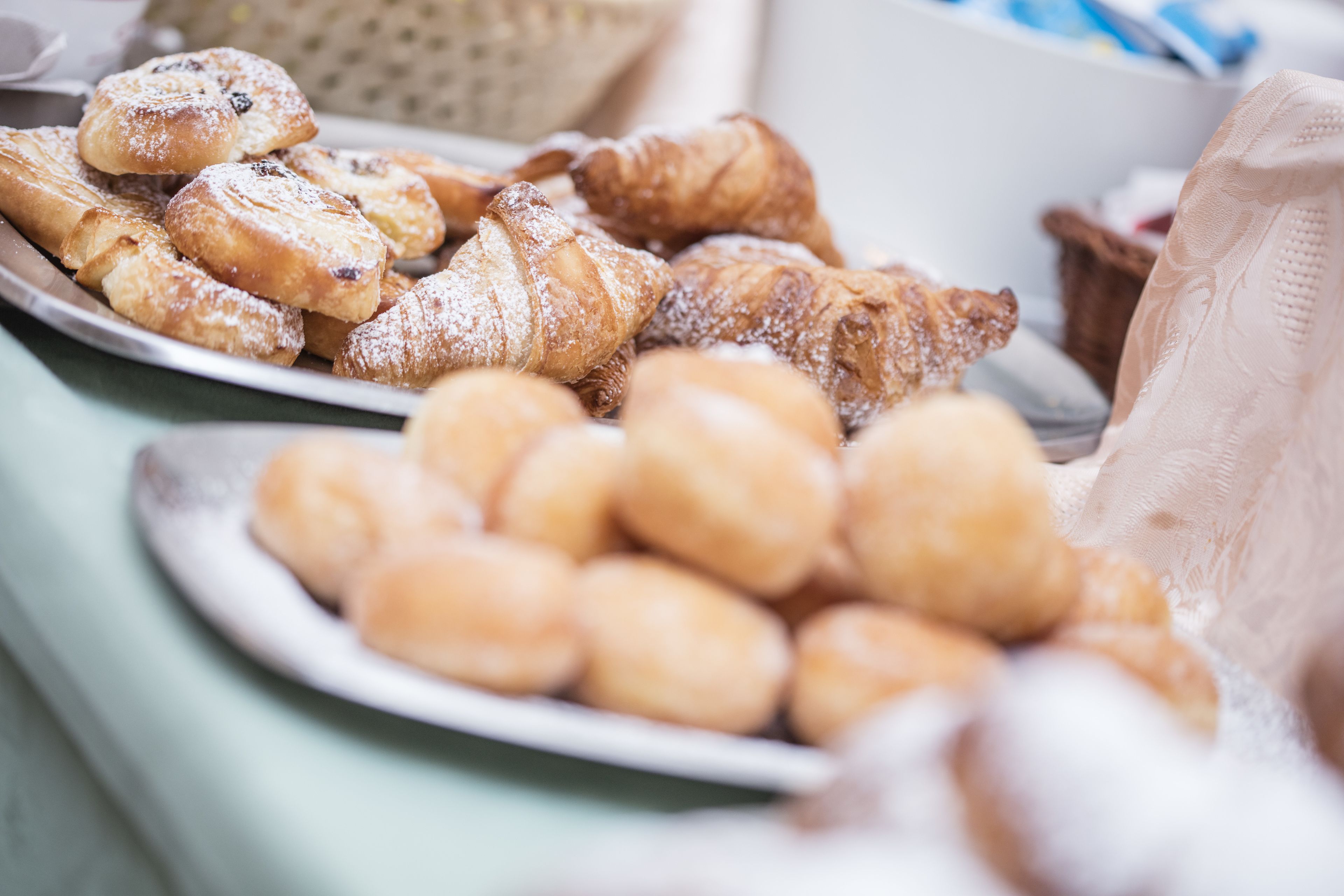 Variedad de pasteles en platos, incluyendo croissants y bollos redondos.