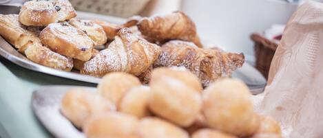 Variedad de pasteles en platos, incluyendo croissants y bollos redondos.