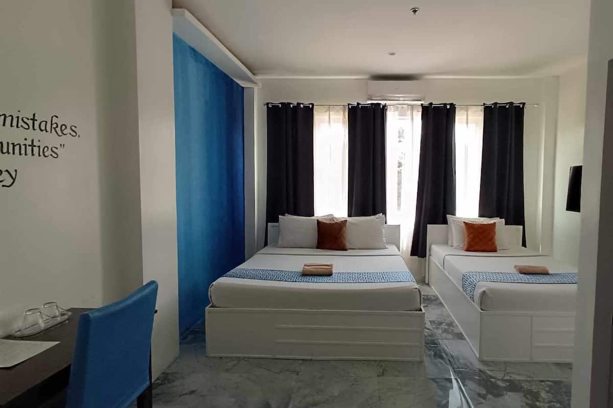 A hotel room with two beds, a desk, and a chair.