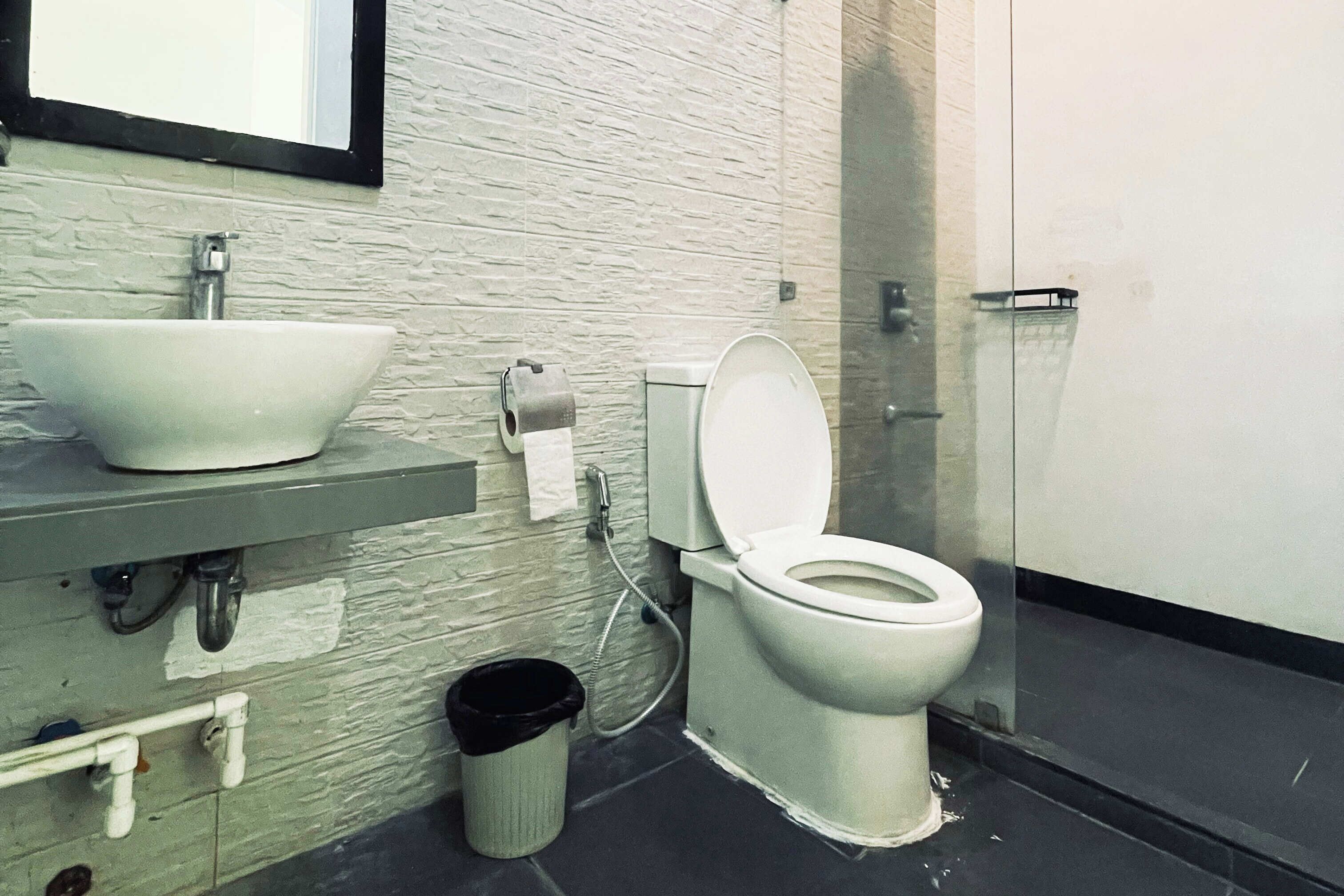 Un baño con un lavamanos blanco, inodoro y un cubo de basura.