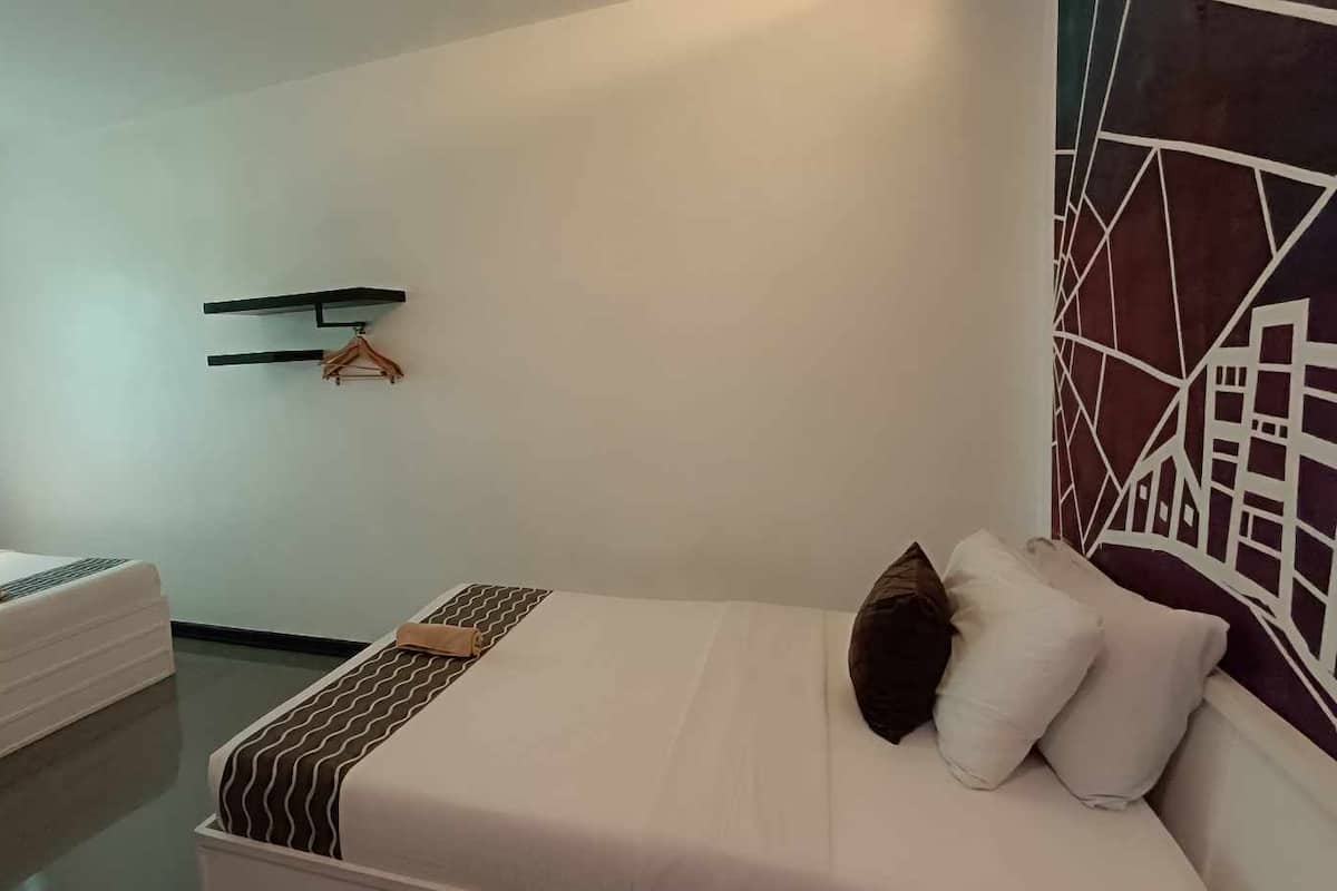 A hotel room with a bed, a sofa, a wall-mounted shelf, and a painting.