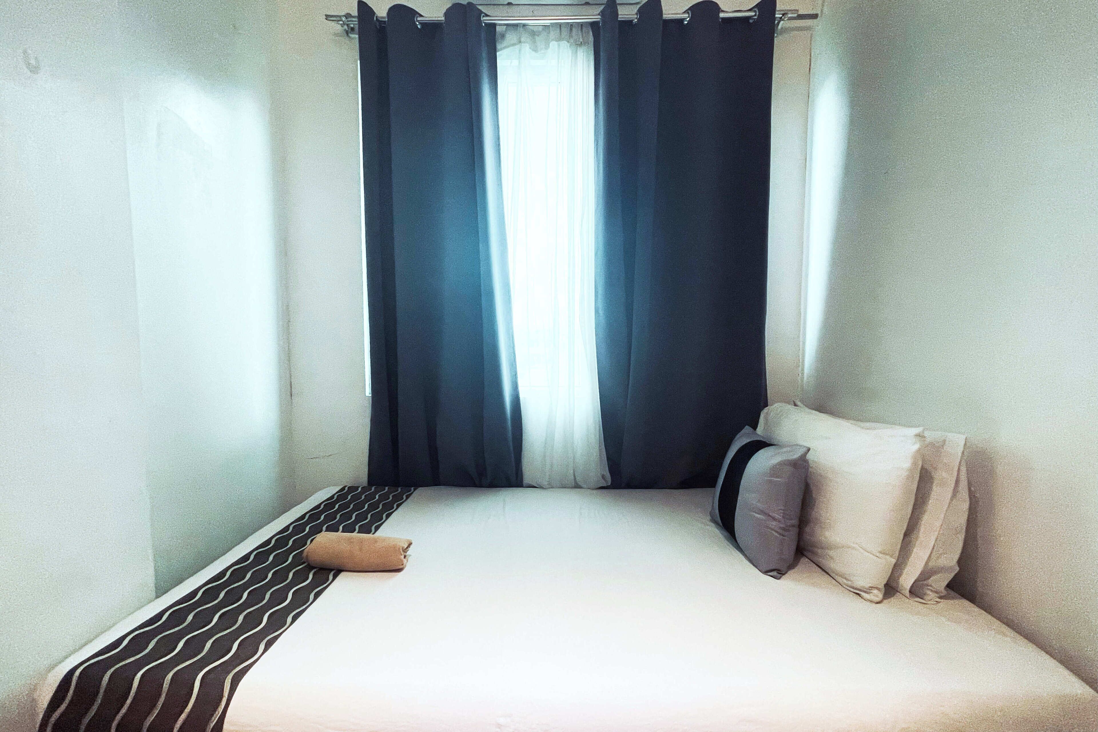A single bed with a striped bedspread, two pillows, and a brown towel.