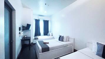 A hotel room with two beds, a small table, and a TV.
