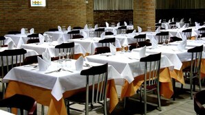 A banquet hall with multiple tables set for dining, featuring white tablecloths and orange chair covers. - Hotel La Unión (Humanes de Madrid)
