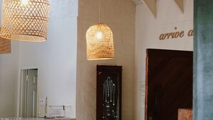 Una sala moderna con un sofá azul, dos lámparas colgantes de mimbre, un mueble de madera y una puerta con el texto "arrive at".