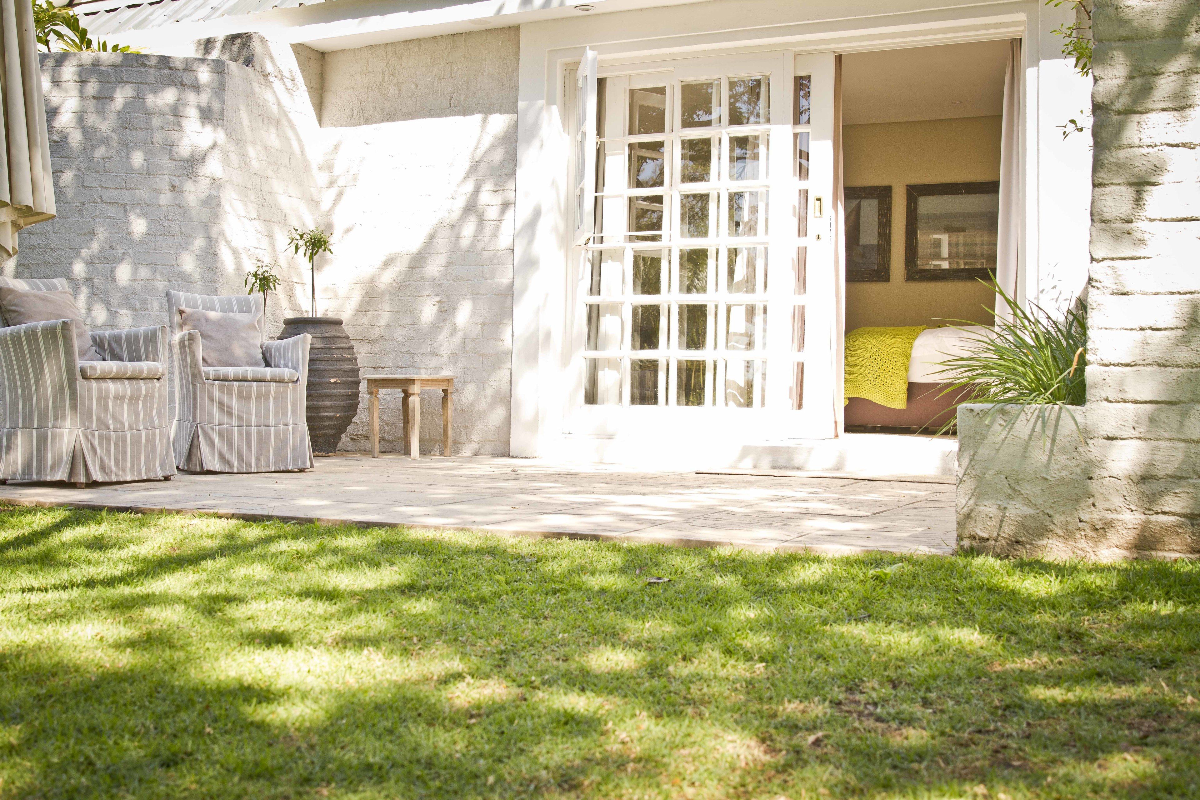 A patio area with two striped chairs, a small table, and a potted plant.