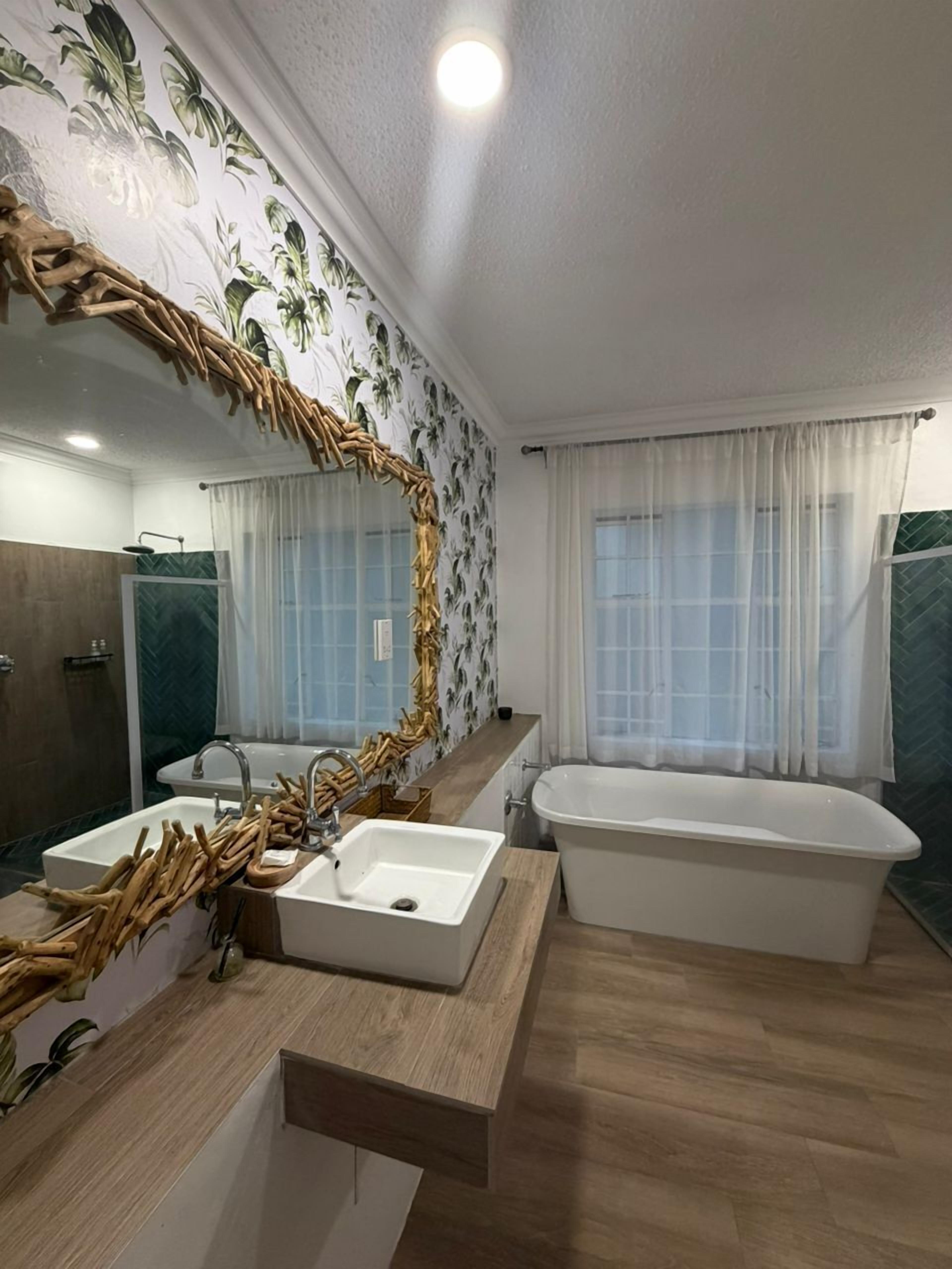A bathroom with a large mirror, two sinks, a bathtub, and a shower area.