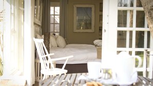 Una habitación con una cama, una mesa con una taza y un plato, y una silla.