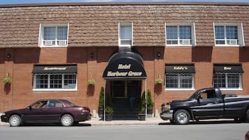 Un hotel llamado 'Harbour Grace' con fachada de ladrillo, un coche estacionado al frente y una camioneta negra a la derecha.