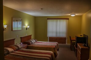 Habitación de hotel con dos camas, un escritorio, una silla, un televisor y una ventana con persianas.