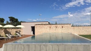 A rectangular swimming pool with a brick wall and a small building entrance.