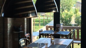 A dining area with a table set for two, a view of greenery and mountains, and two hanging pendant lights. - La Locanda Paradiso (Perugia)
