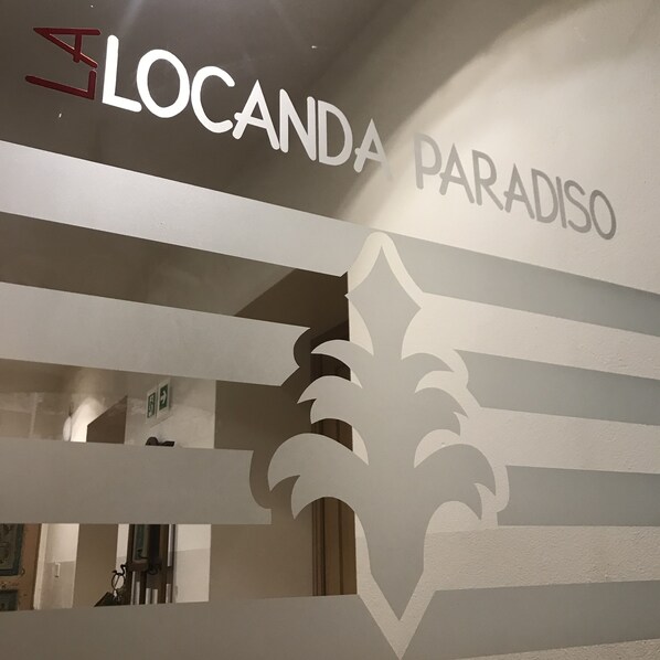 Um letreiro com as palavras 'LOCANDA PARADISO' e um design estilizado de folha.