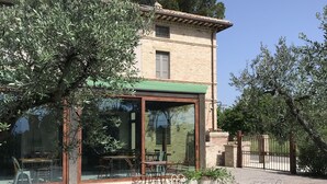 A building with a glass facade, outdoor seating, and a garden area. - La Locanda Paradiso (Perugia)