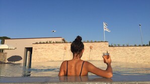 A person in a swimming pool with a clear blue sky and a flag in the background. - La Locanda Paradiso (Perugia)