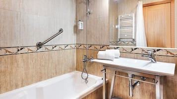 Une salle de bain équipée d’une baignoire, d’un lavabo, d’une douche et d’un porte-serviettes.