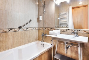 A bathroom with a bathtub, a sink, a shower, and a towel rack. - Hotel Lamacaes (Braga)