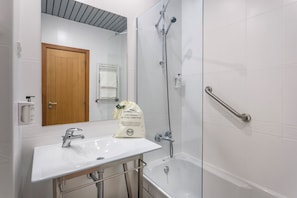 A bathroom with a white sink, a wooden door, a glass shower enclosure, and a white tiled wall. - Hotel Lamacaes (Braga)