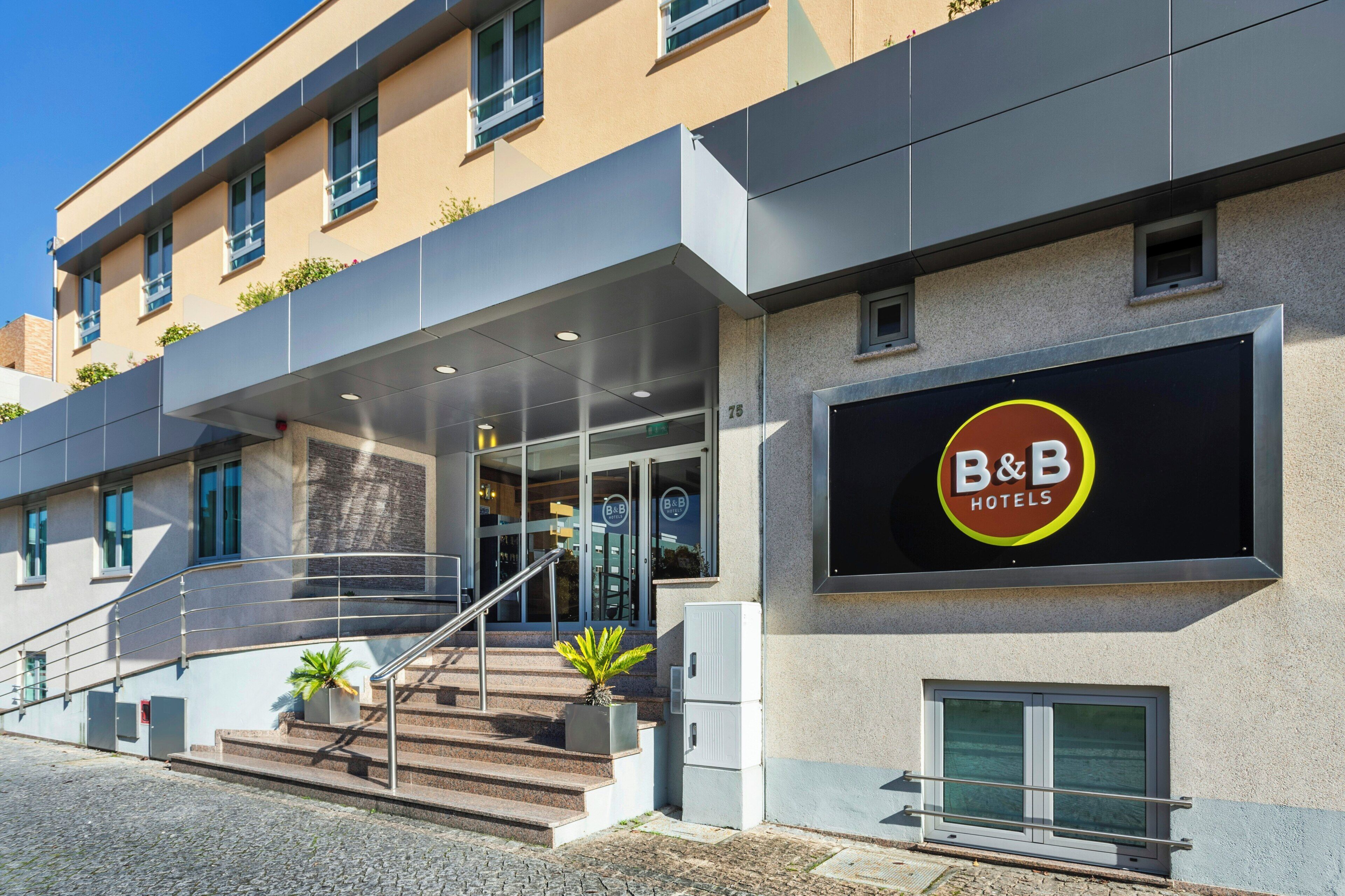 A B&B hotel entrance with a staircase, a signboard, and a modern building facade.