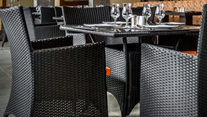 Een restaurant met rieten stoelen en tafels, plafondventilatoren en een decoratieve wand.