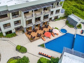 A multi-story hotel with outdoor seating and a swimming pool.