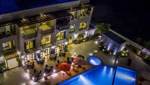 Een meerlaags hotel met een zwembad, buitenzitplaatsen en een goed verlicht terras.