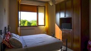 A bedroom with a bed, a window with curtains, a radiator, and a wardrobe. - Poggio delle Rose Tuscany Relais (Chianciano Terme)