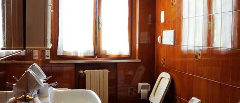 A bathroom with a sink, bidets, a toilet, and a bathtub.