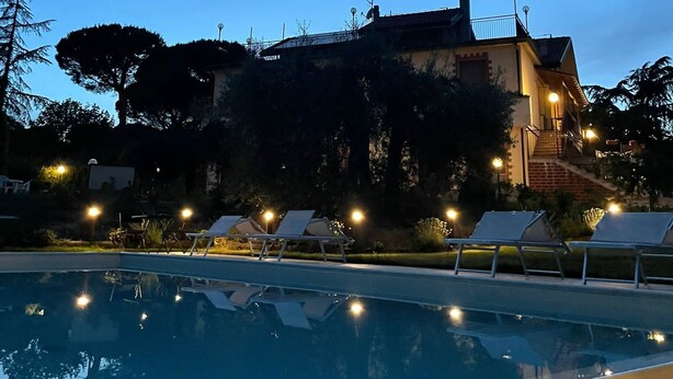 A pool area with lounge chairs, a building with a staircase, and a clear sky. - Poggio delle Rose Tuscany Relais (Chianciano Terme)