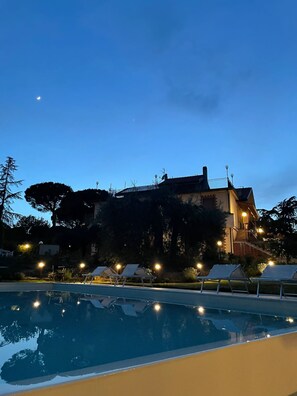 Un área de piscina con sillas de descanso, un edificio con escaleras y un cielo despejado.
