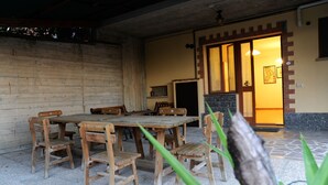 A wooden dining table with chairs, a stone floor, and a doorway leading to a room with a tiled floor. - Poggio delle Rose Tuscany Relais (Chianciano Terme)