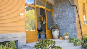 A building entrance with a wooden door, a large potted plant, and a stone wall. - Poggio delle Rose Tuscany Relais (Chianciano Terme)