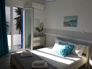 A bedroom with a bed, a nightstand, a dresser, a mirror, and a window with curtains.