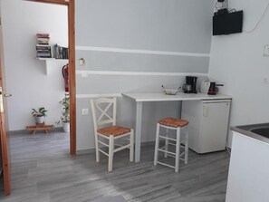 A compact kitchen with two stools, a coffee maker, and a small refrigerator. - Athina Studios (Paros)