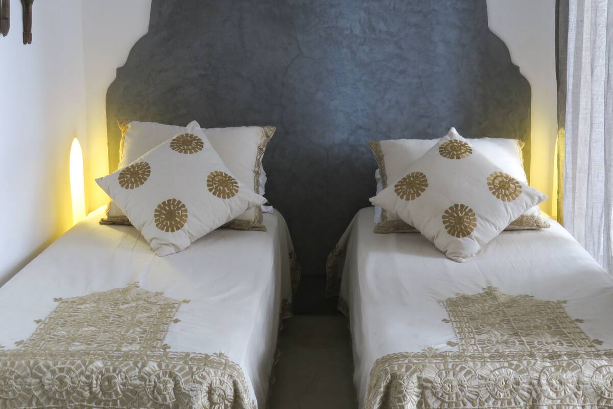 Een kamer met twee bedden, elk met een hoofdbord en decoratieve kussens.