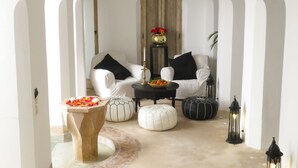 Une pièce comprenant deux fauteuils blancs, une table basse ronde et un meuble en bois orné d’un vase de fleurs.