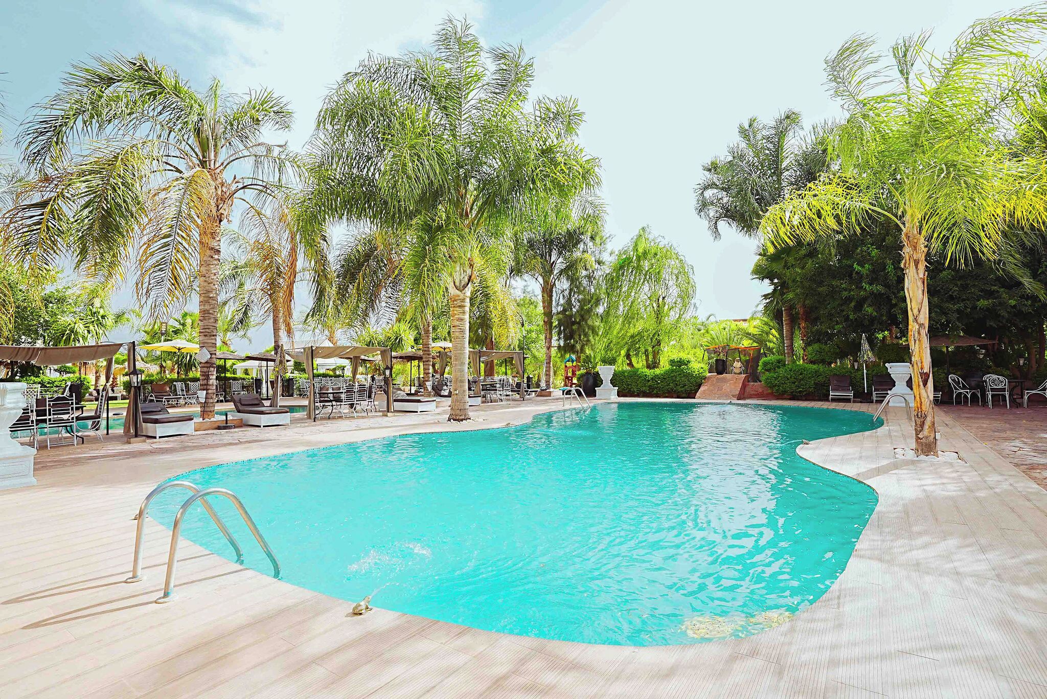 Una piscina al aire libre, sombrillas, sillones reclinables de piscina