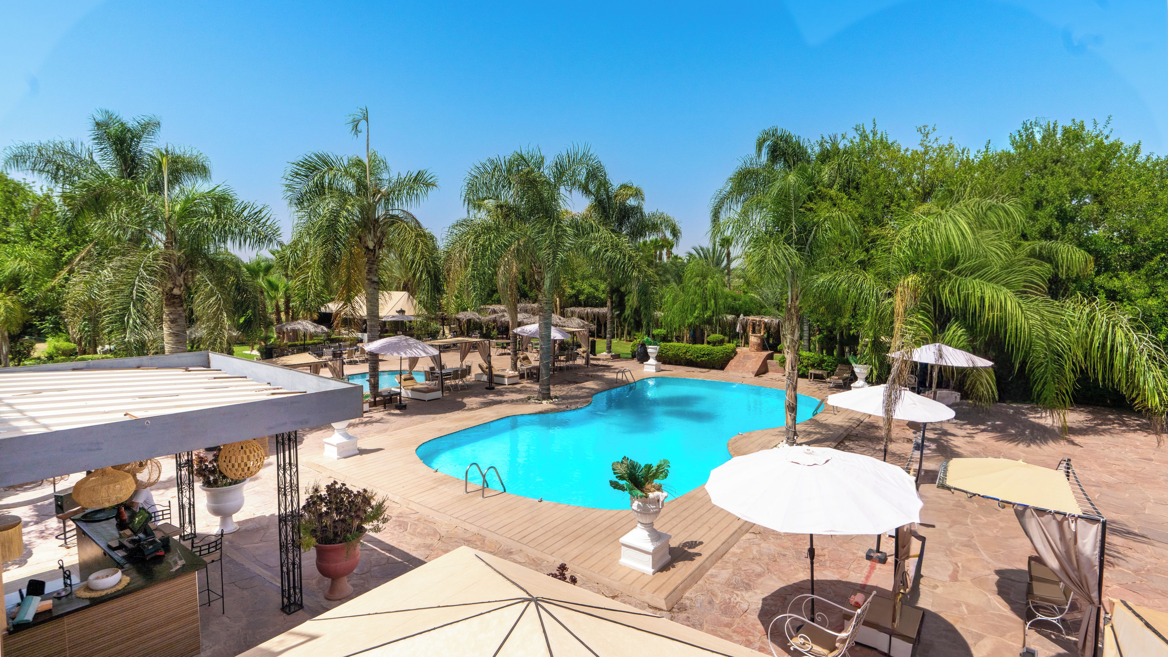 A pool area with lounge chairs, umbrellas, and a reception desk.